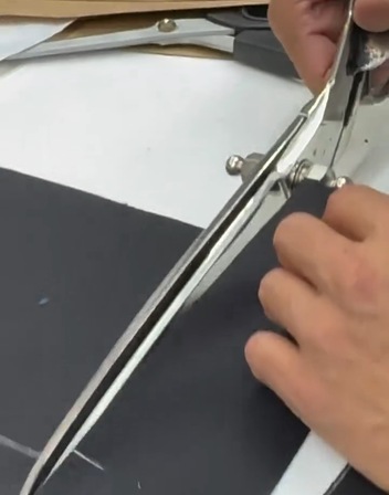 Manos del taller Félix Ramiro cortando un tejido con tijera